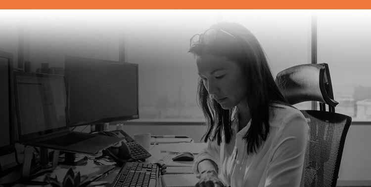 Woman doing work at her desk with Interstaff orange top border for Complex Migration service