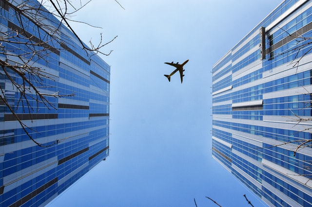 A plane flying over buildings for Visa Entry Conditions 8504