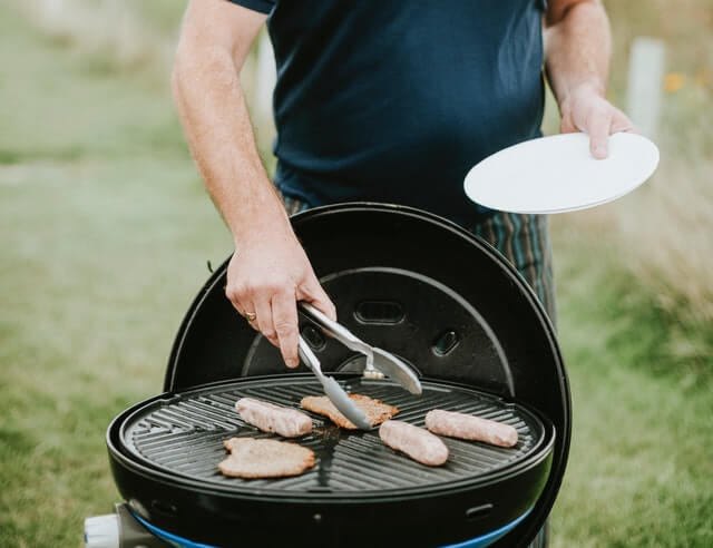 Australia man cooking democracy sausage a BBQ on the grill