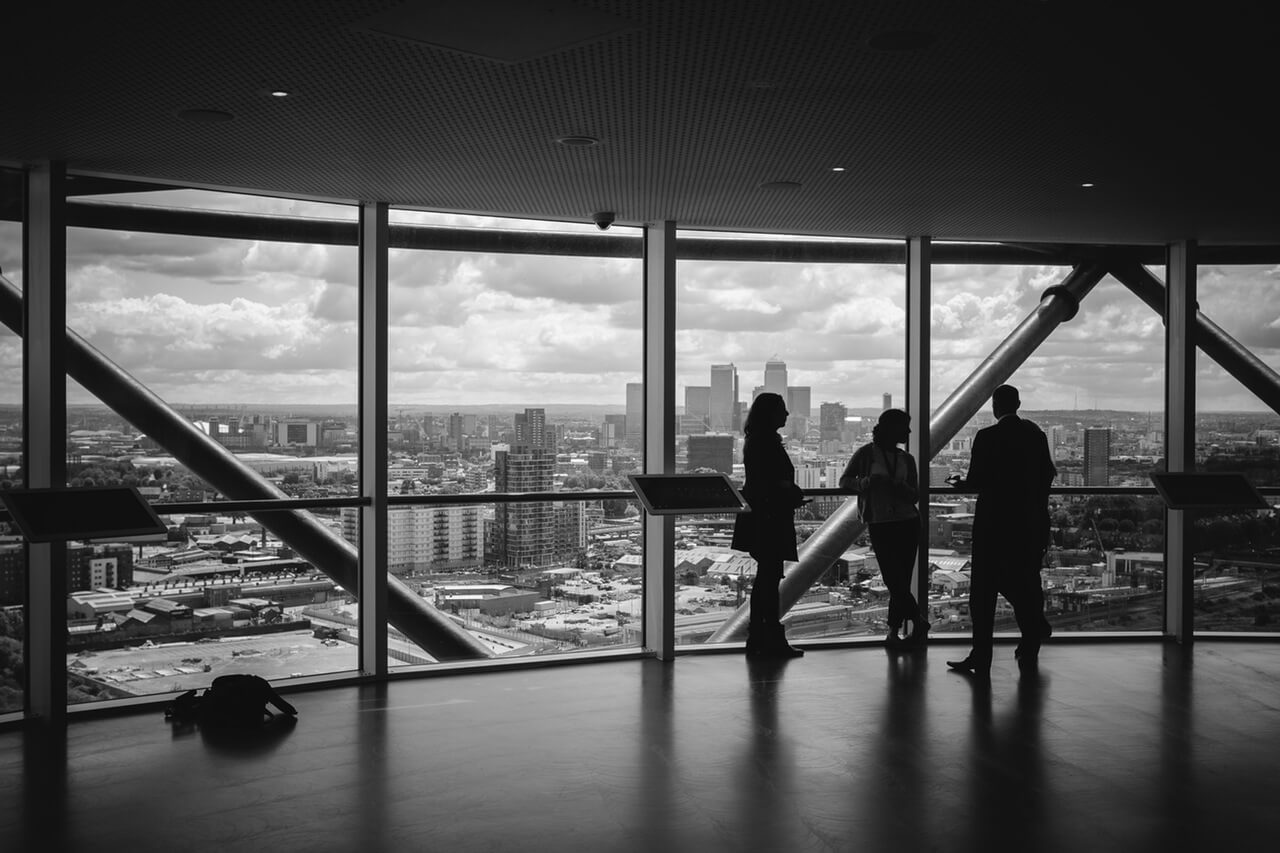 Black and white image of people viewing the city inside of large building