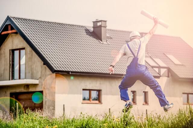 Builder jumping for joy with blueprint plans in his hand