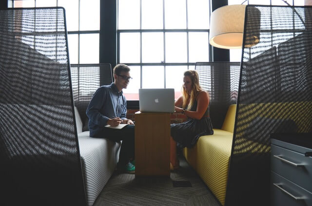 Man and woman sitting in office workspace and collaborating