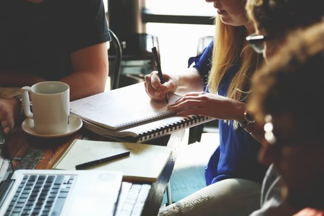Woman writing down notes during group meeting