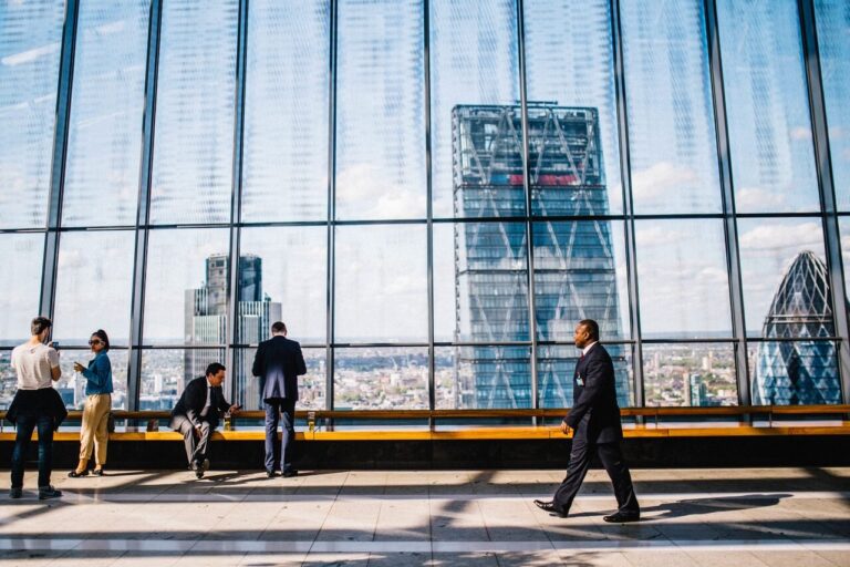 A businessman walking through a skyscraper building with view of city