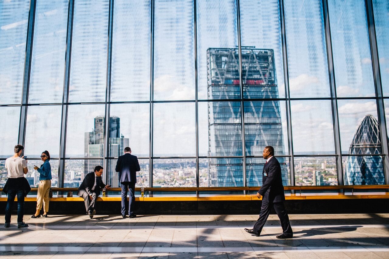 A businessman walking through a skyscraper building with view of city