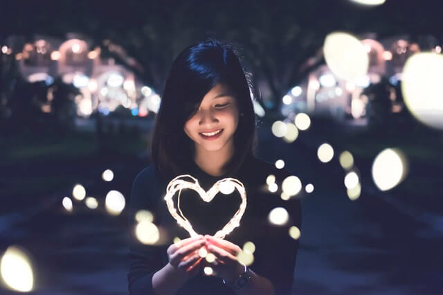 Young Asian woman holding string lights in the shape of a heart for the Perth international arts festival