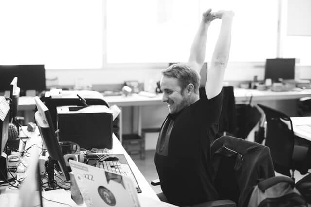 happy worker stretching at his desk
