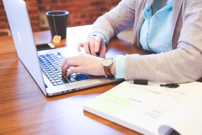 Young woman at Mac laptop with textbook open