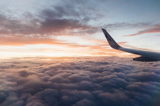 A plane in the air with clouds as background for Australia's economic outlook immigration post by Interstaff