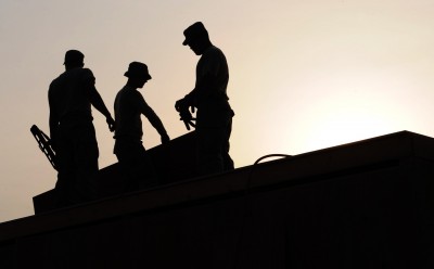 Three construction site workers wearing hardhats in the sun